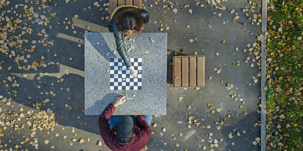 Couple playing chess at table in park during autumn